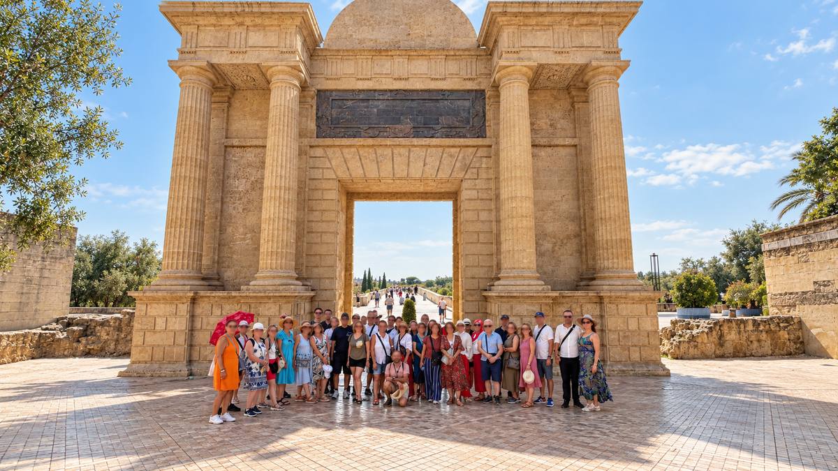 A walking group standing under a stone ceremonial gate near Córdoba.
