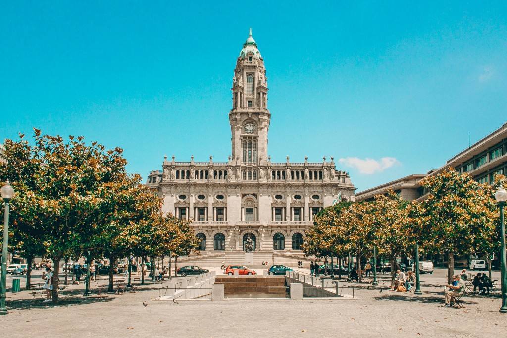 Porto City Hall at the head of Avenida dos Aliados, framed by trees under a clear sky.